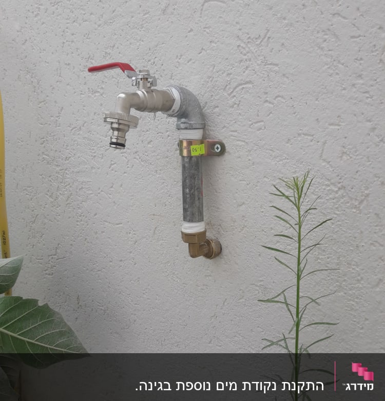 ברז מים עם ידית אדומה על קיר